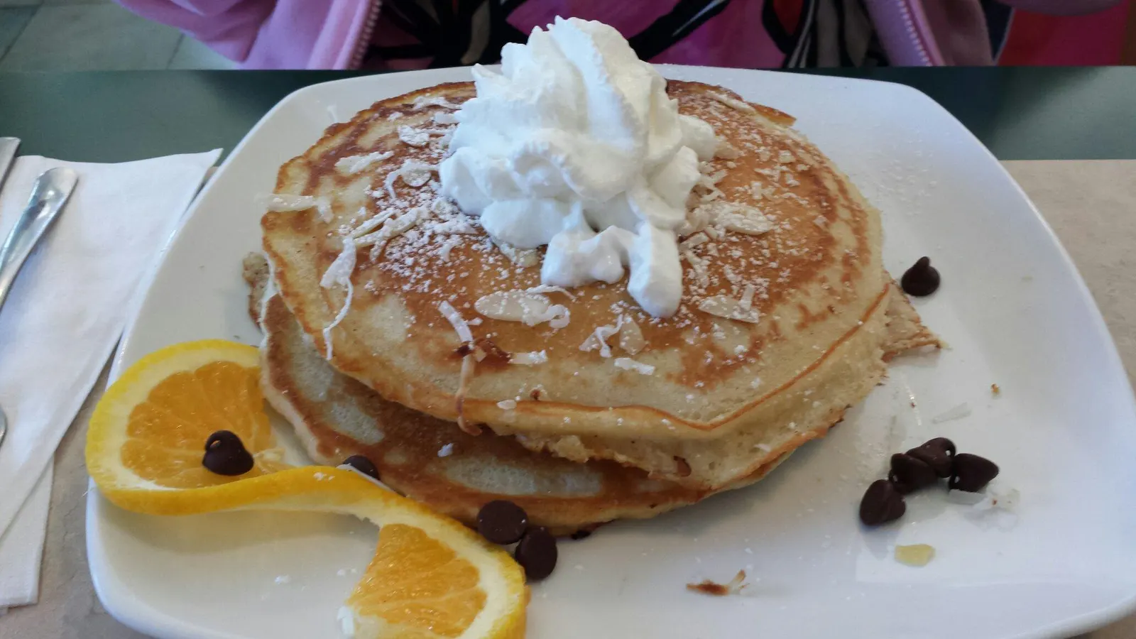 A generous pancake stack topped with whipped cream